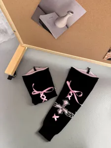 Detailansicht schwarzer Strick-Beinwärmer mit rosa Schleife und Gothic-Kreuz für den Winter.
