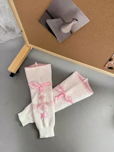Detailaufnahme von Lolita-Knitted-Beinwärmern mit rosa Schleifen und Kreuzmuster.
