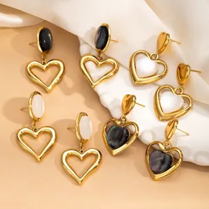 Close-up detail of geometric heart-shaped earrings featuring opal stones on soft fabric.