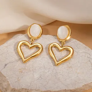 Close-up of retro French style gold cat's eye stone and hollow heart drop earrings detail.