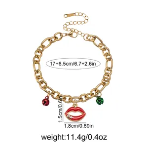 Gold stainless steel chain bracelet detail view showing red lip pendant and small bells.