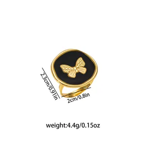 Anello in acciaio inossidabile dorato con smalto nero e dettaglio a farfalla, design aperto.