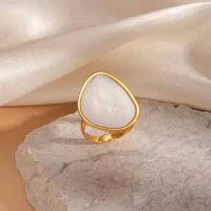 Primo piano dettaglio dell'anello aperto in acciaio inossidabile con goccia bianca e bordo oro