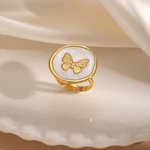 Dettaglio ravvicinato dell'anello in acciaio inossidabile dorato con smalto bianco e farfalla.