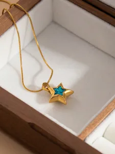 Detailed view of gold-toned pentagram star necklace with sparkling blue crystal center in box.
