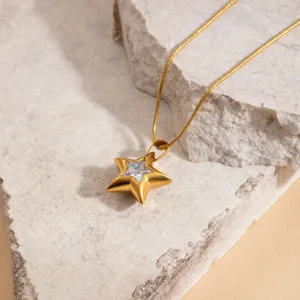 Detailed shot of gold stainless steel star pendant necklace with sparkling stone, dainty collar chain.