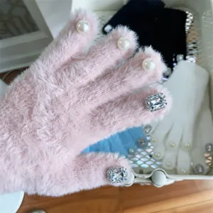 Nahaufnahme von flauschigen Winterhandschuhen mit Perlen und Strasssteinen an den Fingerspitzen.
