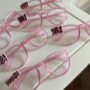 Detailansicht trendy rosa Y2K Brillenmonturen mit verspielten Buchstaben-Anhängern.