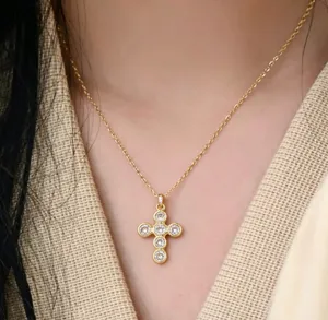 Nahaufnahme einer minimalistischen goldenen Kreuzhalskette besetzt mit Kristallen