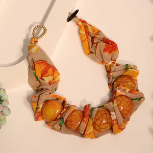 Detailed close-up of bohemian floral print fabric necklace with large amber-textured beads