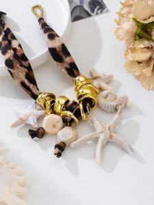 Primer plano de un collar de leopardo bohemio con colgantes de estrella de mar y concha