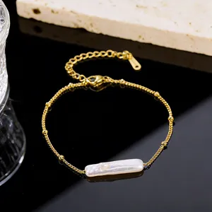Close-up detail of a minimalist gold chain bracelet featuring a long rectangular baroque pearl