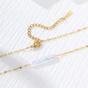 Close-up detail of gold stainless steel extension chain and a long bar pearl pendant