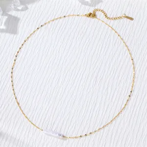 Detail of minimalist gold chain necklace with a long freshwater pearl pendant.