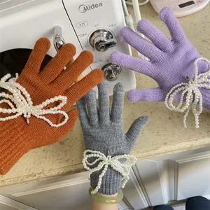 Detailaufnahme von gestrickten Touchscreen-Handschuhen mit eleganter Perlenschleife.