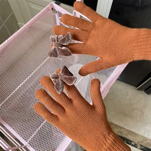 Detailaufnahme der orangefarbenen Strick-Touchscreen-Handschuhe mit süßer Samtschleife.