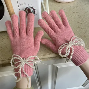 Detailaufnahme rosafarbener Strickhandschuhe mit eleganten Perlen Schleifen für warme Wintertage.