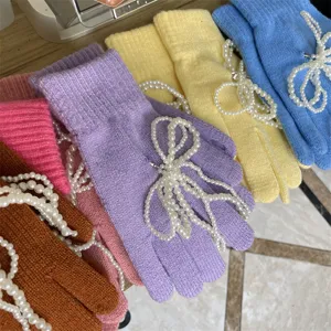 Detailansicht von bunten Strickhandschuhen mit wunderschönen Perlen-Schleifen verziert.