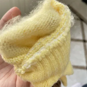 Nahaufnahme des gelben flauschigen Strickhandschuhs, weiche Wolle, warmer Winterdetail.