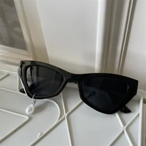 Schwarze Cat-Eye-Sonnenbrille mit Perlenanhänger-Detail, trendiges Design für Outfits.