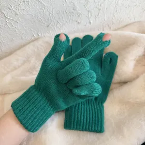 Nahaufnahme dunkelgrüner Strickhandschuhe mit fingerlosem Design und Rippbündchen.