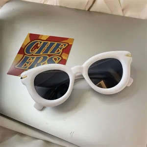Nahaufnahme der trendigen weißen klobigen Sonnenbrille mit dunklen Gläsern und goldenen Details.