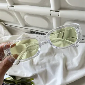 Detailaufnahme von Retro Rechteckige Sonnenbrille mit klarem Rahmen und gelben Gläsern.