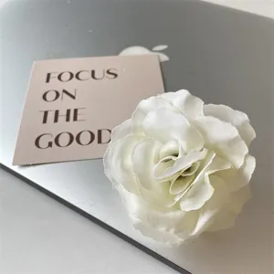 Detailaufnahme einer weißen Stoffblumen-Haarspange mit mehrschichtigem Blütenblatt-Design.