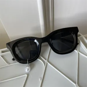 Detailansicht der trendigen schwarzen Sonnenbrille mit einzigartigem Perlenanhänger.
