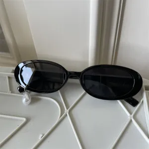 Modische schwarze ovale Sonnenbrille mit Perlenanhänger, einzigartiges Nischen-Cat-Eye-Detail.