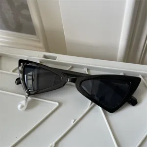 Nahaufnahme schwarzer Cat-Eye-Sonnenbrille mit stilvollem weiße Perlenanhänger.