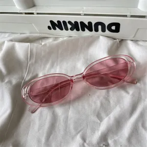 Nahaufnahme von trendigen rosa transparenten ovalen Sonnenbrillen mit Bonbonfarben.