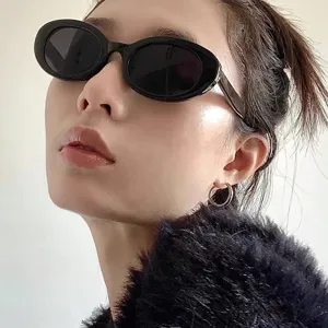 Detailaufnahme der Retro-Ovallsonnenbrille am Modell mit stilvollem schwarzem Rahmen.