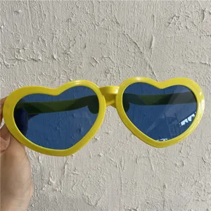 Uebergroesse Herz-Sonnenbrille mit gelben Gestellen und blauen Glaesern fuer Party.