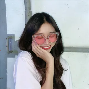 Nahaufnahme modischer pinker Strass-Sonnenbrille mit funkelnden Kristallen und getönten Gläsern.