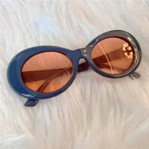 Nahaufnahme von retro dicken ovalen Sonnenbrillen mit dunkelblauen Gestellen und orangen Gläsern.