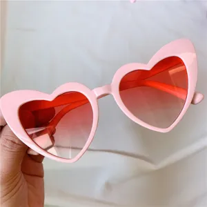 Detailaufnahme der rosa Herz Katzenaugen Sonnenbrille mit roten Farbverlaufsgläsern.
