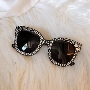 Detailansicht großer schwarzer Damen-Sonnenbrillen mit Strass-Sternen und UV-Schutz-Gläsern.