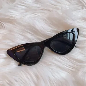 Schwarze Cat-Eye-Sonnenbrille Detailansicht auf weißem Fellhintergrund im Retrostil.