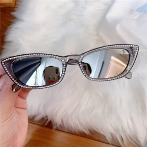 Detailansicht retro schmaler Sonnenbrille mit funkelnden Strasssteinen und reflektierenden Gläsern.