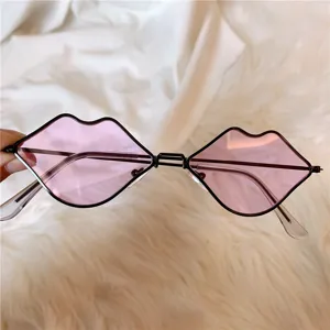 Lippenform Sonnenbrille Detail, rosa getönte Gläser und schmaler schwarzer Metallrahmen.