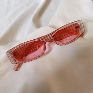 Modische schmale rechteckige Sonnenbrille mit glitzernden Strasssteinen und rosa Glaesern.