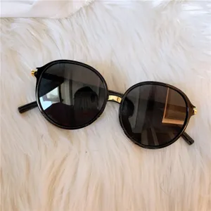 Detaillierte Nahaufnahme stilvoller schwarzer runder Oversize-Sonnenbrille mit goldenem Steg.