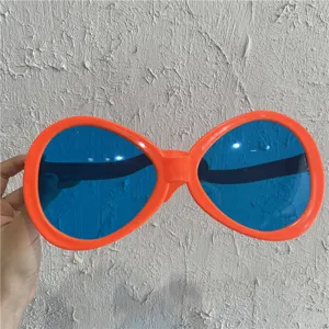 Nahaufnahme von riesigen Party-Sonnenbrillen mit orangen Rahmen und blauen Gläsern als Requisite.