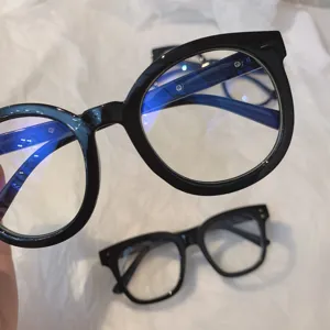 Primer plano detallado de elegantes gafas con montura negra gruesa y lentes anti luz azul.