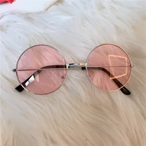 Nahaufnahme von retro runden rosa Sonnenbrillen mit silbernem Metallrahmen auf weißem Flauschgrund.