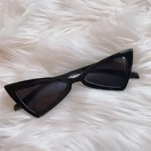 Detailaufnahme von schwarzen Vintage-Dreiecks-Cat-Eye-Sonnenbrillen auf flauschigem Kunstpelz.