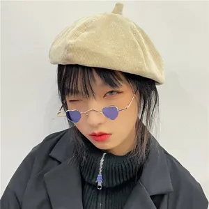 Detailaufnahme einer trendigen kleinen Sonnenbrille in Herzform mit lila Gläsern und Goldgestell.