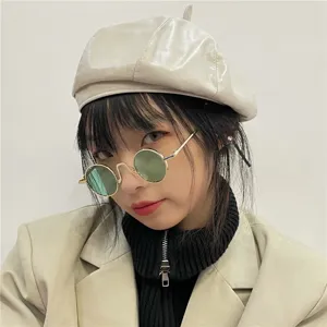 Detail shot of vintage round metal frame sunglasses with green tinted lenses, stylish look.