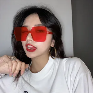 Close-up detail of oversized red square sunglasses on model, stylish retro eyewear.